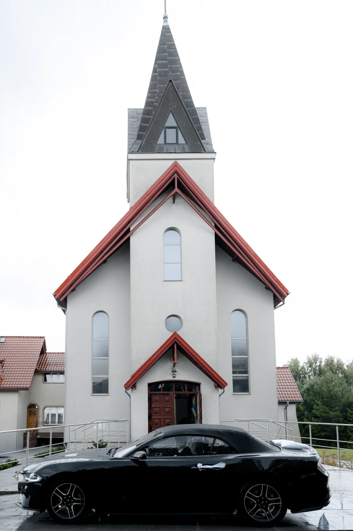 Czarny Ford Mustang Cabrio przed kościołem
