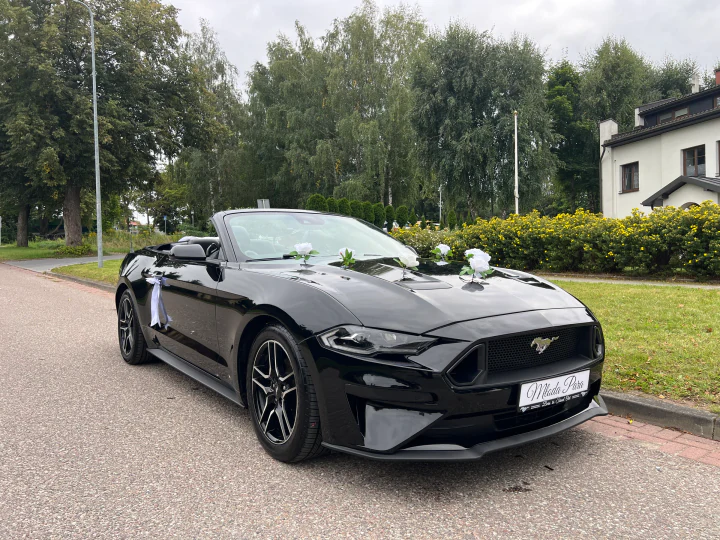 Czarny Mustang z otwartym dachem i kwiatową dekoracją, widok od prawego przodu